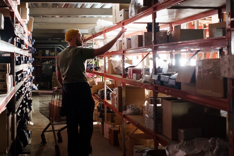 lone worker picking objects off warehouse shelf